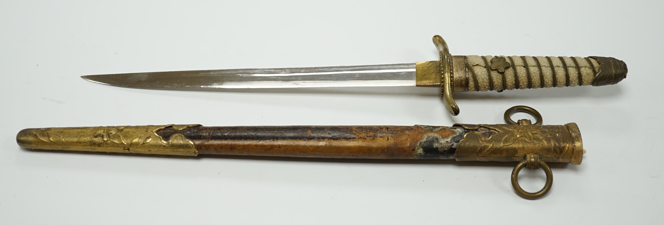 A dagger with brass fittings and a shagreen grip, in a leather covered scabbard, blade 21cm. Condition - losses to leatherwork and scabbard, splits to shagreen grip and some wear overall.